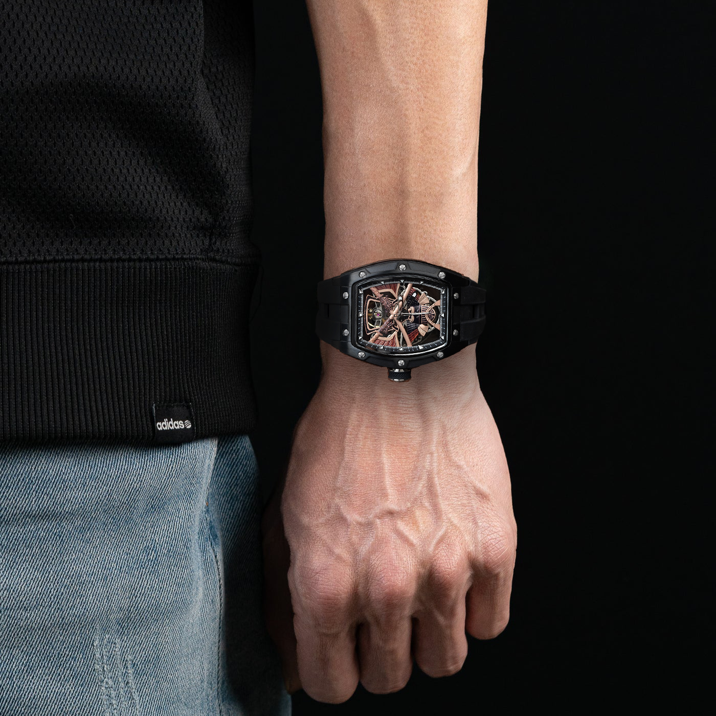 Person wearing a black watch on a dark background